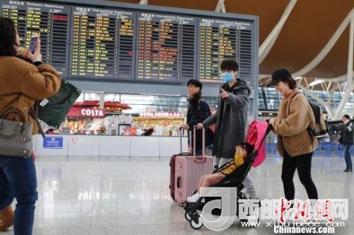 旅客帶著孩子前往辦票柜臺辦理登機手續(xù)?！∫罅⑶?攝