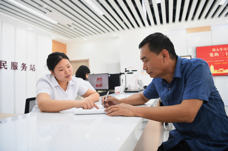 2023年5月23日，河北雄安新區(qū)容東片區(qū)南文營社區(qū)居民（右）在社區(qū)便民服務(wù)站辦理業(yè)務(wù)。